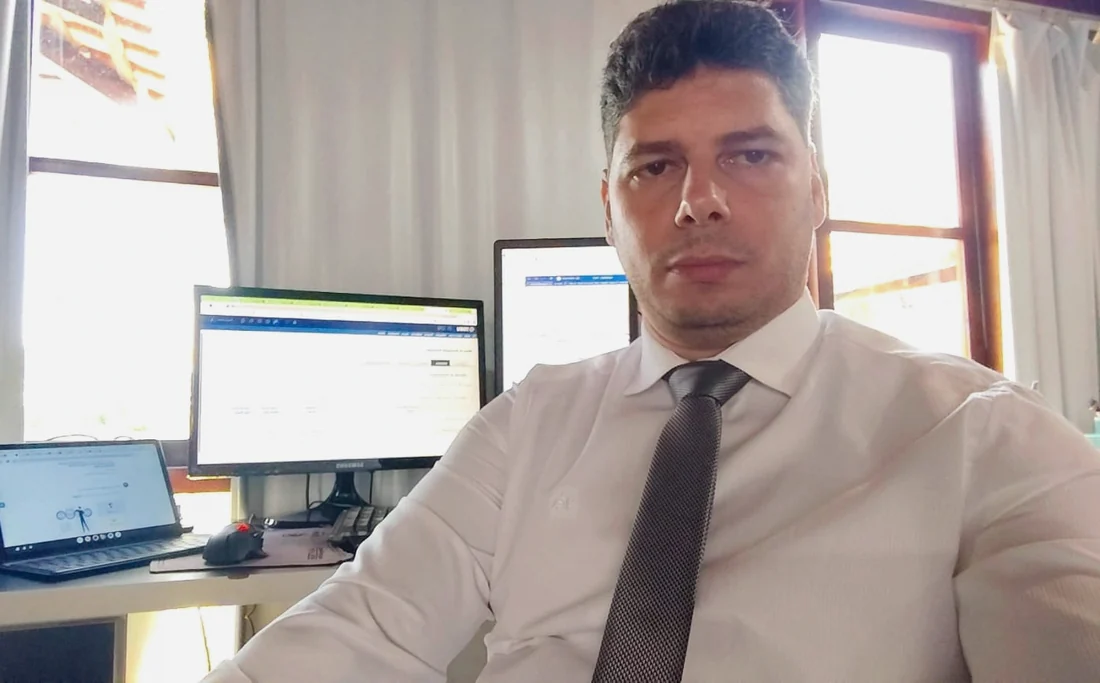 Flávio Cruz trabalhando na mesa do escritório, com dois monitores abertos.